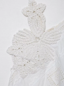 Detail of white crochet top featuring 3D floral lace patterns and intricate wave trim