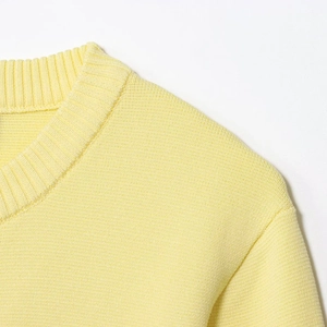 Dettaglio del girocollo a costine e della trama a maglia fine sul cardigan giallo