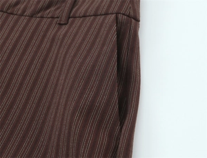 Detail of brown pinstripe pants showing waist tailoring and side pocket stitching
