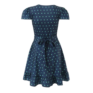 Detailed close-up of dark blue dress with green floral patterns and ruffled hem edges