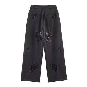 Detail of high-waist striped trousers with black sequin flower embroidery and back pockets