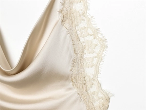 Detail of champagne satin dress featuring elegant eyelash lace trim and silky texture
