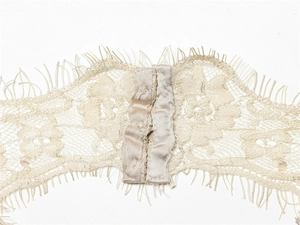 Detailed macro view of beige eyelash lace fabric and silk binding with hook closure