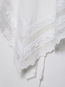 Detailed view of white floral lace embroidery with scalloped ruffles and ties