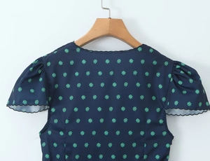 Detail of navy blue puff sleeve with daisy print and scalloped black wavy trim edge