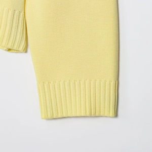 Dettaglio macro del polsino a coste su un cardigan in maglia giallo chiaro donna
