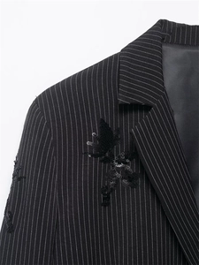Detail of pinstripe blazer featuring black sequin angel embroidery on the chest