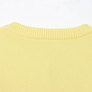 Dettaglio ravvicinato dello scollo a costine e della trama a maglia del cardigan giallo