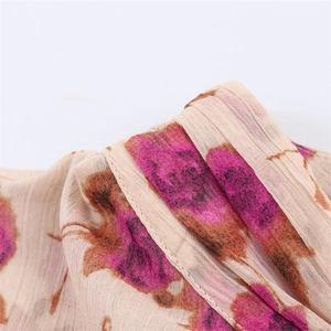 Close-up of lightweight pleated chiffon fabric with elegant pink floral print and stitching