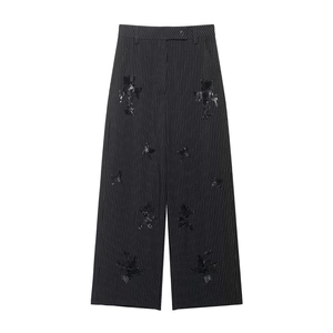 Close-up of black high-waisted wide-leg trousers with vertical stripes and sequins