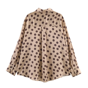 Detail view of the back pleat and dark brown polka dots on a satin shirt fabric