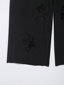 Detail of high-waisted black pinstripe trousers with sequined floral embroidery decor
