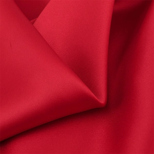 Close-up of premium red satin fabric showing smooth silk texture and twill weave detail