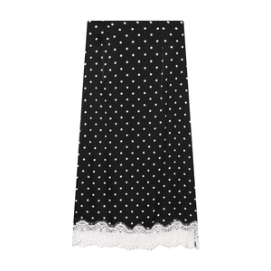 Detailed close-up of white lace trim on a black polka dot midi skirt hemline