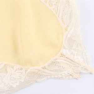 Detail of light yellow fabric featuring delicate cream eyelash lace and floral patterns