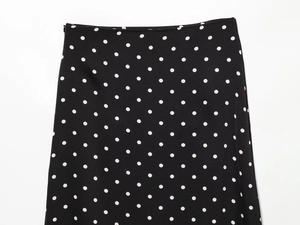 Close-up detail of classic black and white polka dot skirt with zipper and smooth texture