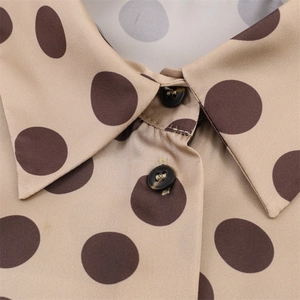 Detailed view of the pointed collar and buttons on a silky polka dot shirt for women
