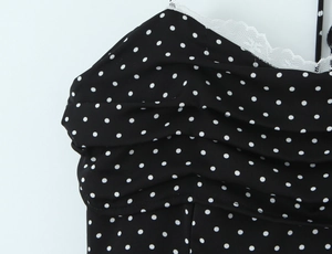 Détail du tissu à pois noirs avec bordure en dentelle blanche et corsage plissé
