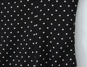 Gros plan sur le motif à pois blancs et couture fine sur tissu de robe noire d'été