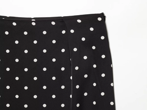 Close-up of black and white polka dot skirt showing side invisible zipper and waist detail