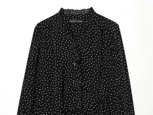 Detail of ruffled stand collar and button front on black polka dot long sleeve top