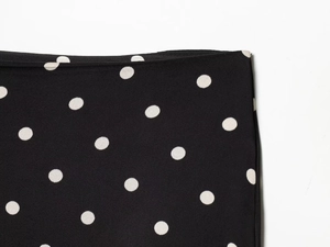 Macro detail of black and white polka dot fabric with precise stitching and fine texture