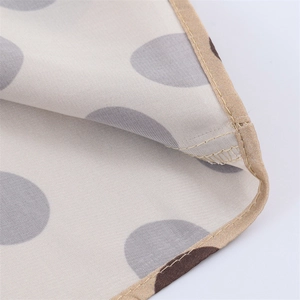 Macro view showing beige satin fabric texture with grey polka dots and neat khaki piping