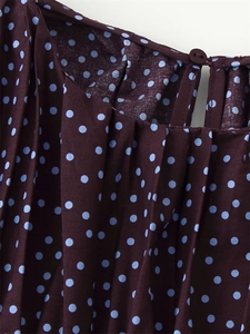 Detailed view of polka dot blouse neckline with delicate pleats and button closure