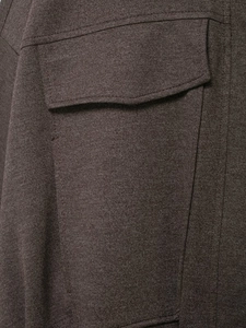 Detailed close-up of dark brown jacket fabric texture and flap pocket stitching detail