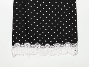 Close-up of black polka dot fabric with delicate white floral lace hem detailing