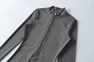 Detail view of smooth high-elastic dark grey yoga bodysuit with standing collar and zipper