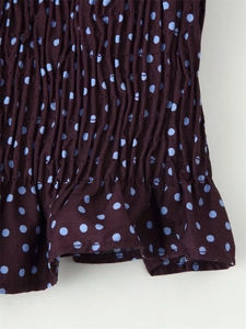 Macro detail showing smocked elastic fabric with polka dot pattern and ruffle hem