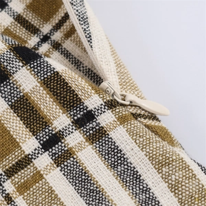 Detail of checkered woven fabric and hidden zipper on a brown plaid cushion cover