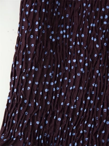 Macro detail of elastic smocked fabric with blue polka dots on a dark background
