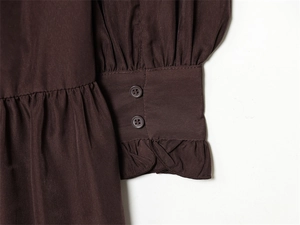 Detail of dark brown dress sleeve featuring double buttons and elegant ruffled cuffs