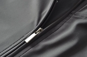 Macro shot of silver metal zipper detail on dark grey high-stretch athletic fabric