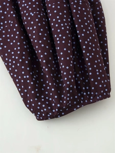 Detail showing high-quality pleats and light blue polka dots on dark woven fabric