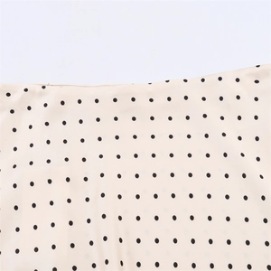 Detailed macro view of lightweight polka dot fabric showing precise stitching and beige texture