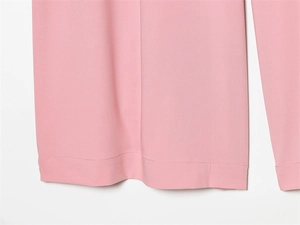 Close-up of pink casual trousers showing smooth fabric texture and neat hem stitching