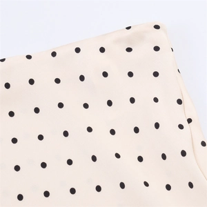 Detailed view of lightweight off-white chiffon fabric with classic black polka dot pattern