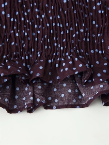 Detail of blue polka dot blouse featuring elastic smocked texture and ruffle hemline