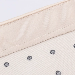 Detailed macro view of the champagne satin trim and black polka dot fabric stitching