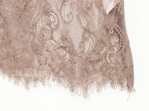 Detailaufnahme von floralem Wimpernspitzenstoff an einem französischen Kleid