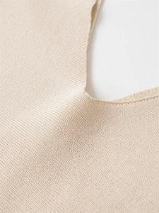 Close-up of the beige knit sweater neckline showing precise stitching and fabric texture