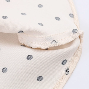 Detailed close-up of beige polka dot fabric with high-quality overlock stitch finish