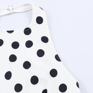 Detailed view of white polka dot top featuring neck button closure and fabric texture