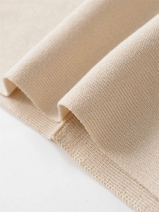 Detailed close-up of cream knit sweater showing soft ribbed texture and premium fabric
