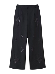 Detail of high-waisted black pinstripe wide-leg trousers with textured patchwork details