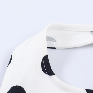 Detail shot of black polka dots on white fabric showing quality double-stitching seams
