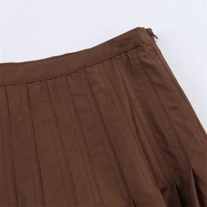 Detail of dark brown pleated skirt showing waist stitching and hidden side zipper